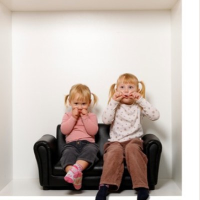 Zwei Schwestern sitzen lachend auf kleinem Sofa