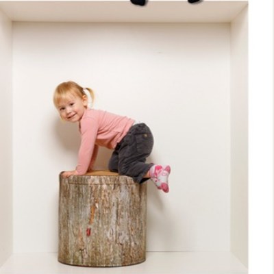 Mädchen klettert auf Baumstamm